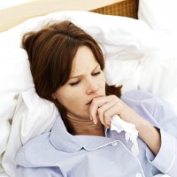 Sick Young Woman Lying in Bed --- Image by © Royalty-Free/Corbis