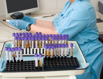 nurse feeds data of test tubes with blood for analysis into the database