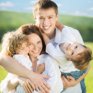 Happy family having fun outdoors in spring field against blue sky background