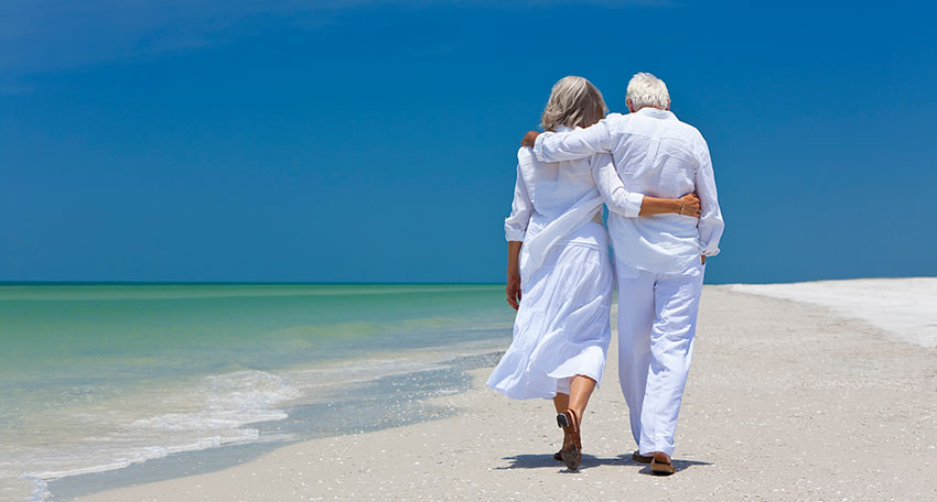 Senior couple walking on the beach discussing the Issels difference.